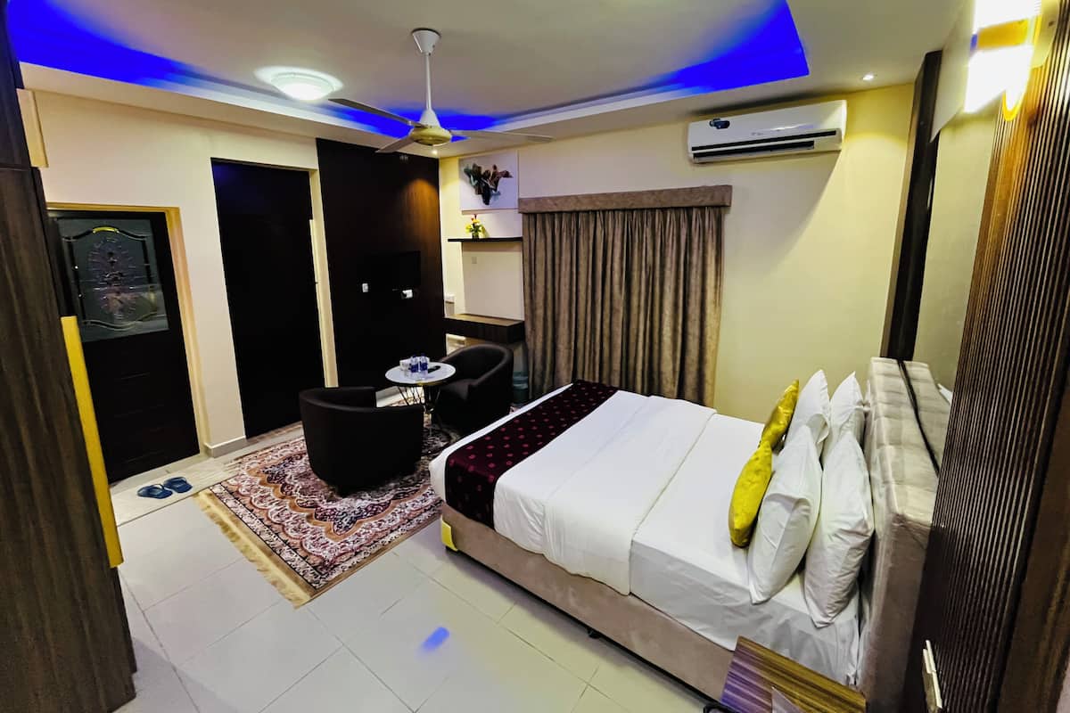 Ein Hotelzimmer mit Bett, Schreibtisch, Stuhl, Deckenventilator und Klimaanlage.