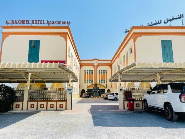 A hotel with a central entrance, two wings, and a covered parking area.
