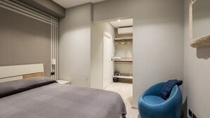 A modern bedroom with a bed, a blue chair, and a walk-in closet. - Mandria Apartments 2 (Bologna)