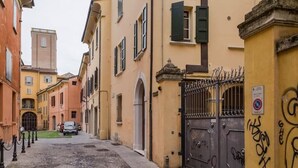 A narrow street with buildings on both sides, a gated entrance, and a parked car. - Mandria Apartments 2 (Bologna)
