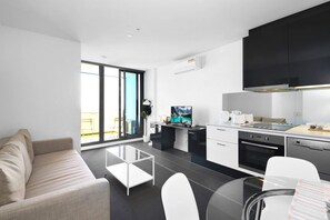 A modern kitchen with a dining area, a sofa, and a large window.
