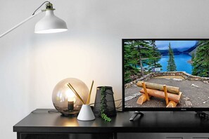 Un bureau sur lequel se trouve un écran d’ordinateur affichant une vue panoramique sur un lac, une lampe de bureau, un objet sphérique en verre et une petite plante.