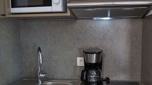 A compact kitchen with a microwave, coffee maker, and a sink. - Pure Thermal Résidence (Roquebilliere)