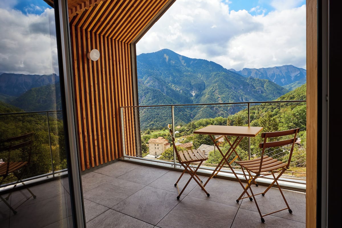 Ein Balkon mit Blick auf Berge, Holzmöbel und eine Glastür.