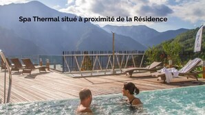 A spa thermal pool with wooden deck and lounge chairs, surrounded by mountains. - Pure Thermal Résidence (Roquebilliere)