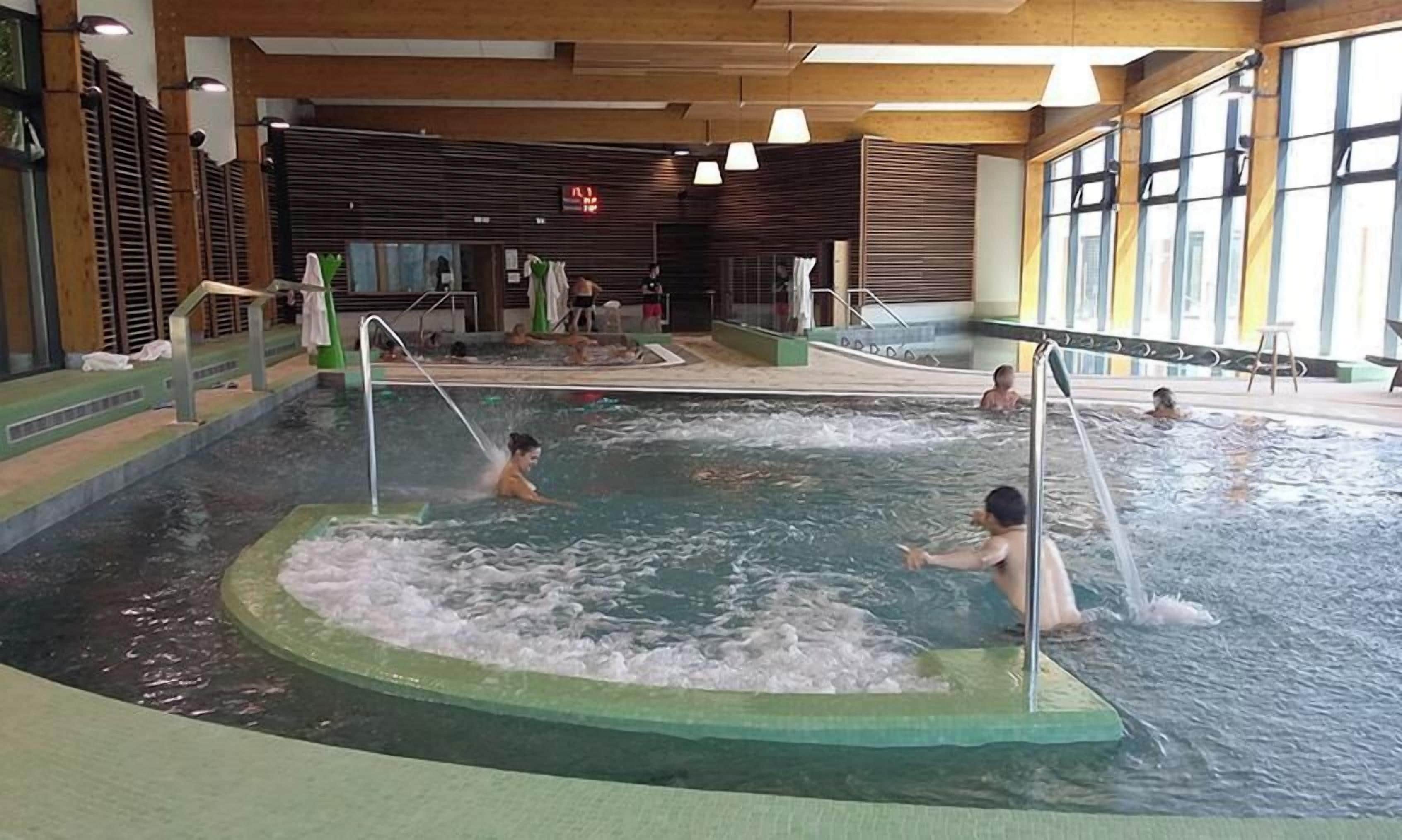 An indoor swimming pool with multiple lanes and a central hot tub area.