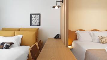 Habitación de hotel con dos camas, una mesa de madera, una obra de arte enmarcada en la pared y un teléfono sobre la mesa.