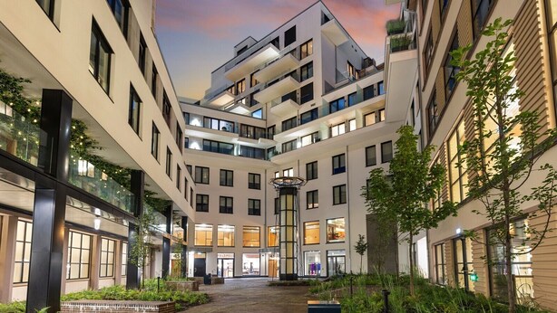 A modern urban building complex with multiple floors, large windows, and a central courtyard. - A-One Homes Sommerro (Oslo)