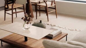 A modern living room with a wooden coffee table, a vase with dried flowers, a book, and a textured rug. - A-One Homes Sommerro (Oslo)