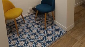 A narrow hallway with two chairs, one yellow and one blue, and a patterned floor. - Appartement aux Portes de Paris, Métro 12 (Aubervilliers)