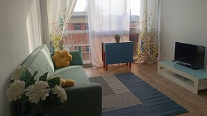 A modern living room with a sofa, a TV, and a small table with a plant. - Appartement aux Portes de Paris, Métro 12 (Aubervilliers)