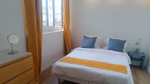 A bedroom with a bed, a dresser, a bedside table, and a window with curtains. - Appartement aux Portes de Paris, Métro 12 (Aubervilliers)