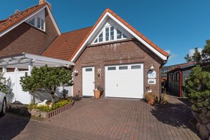 A two-story house with a brick facade, a red-tiled roof, and a white garage door.