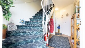 A staircase with a blue leaf-patterned carpet, a white spiral railing, and a red fire extinguisher. - Welcome to the Sylti 3 apartment (List auf Sylt)