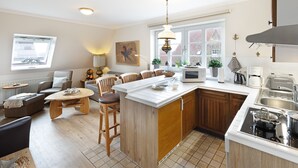 A modern kitchen with a central island, wooden cabinets, and a dining area with a sofa and chairs.