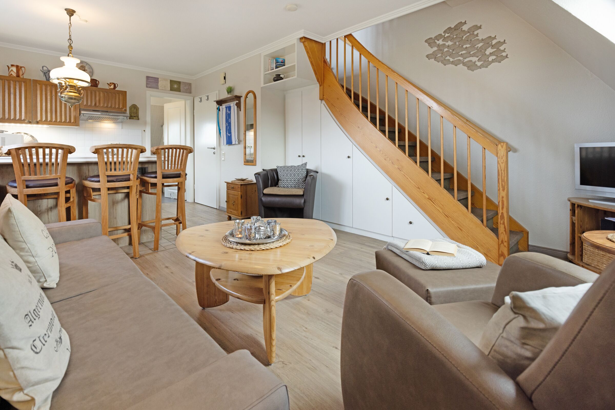 Ein geräumiges Wohnzimmer mit einer Holztreppe, einer Essecke mit Holzsesseln und einer gemütlichen Sitzecke.