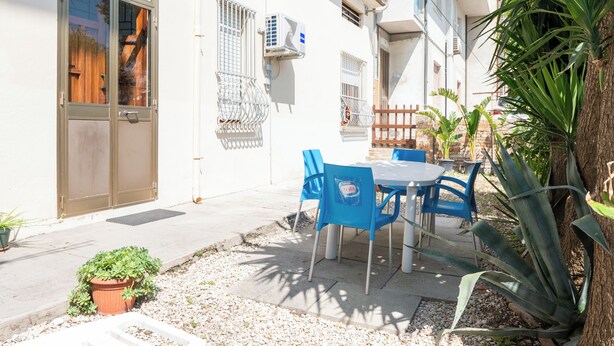 Eine Terrasse mit Tisch, Stühlen, einem Blumentopf und einer Tür.