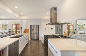 Eine moderne Küche mit Edelstahlgeräten, einer zentralen Kochinsel und Blick in den Essbereich.