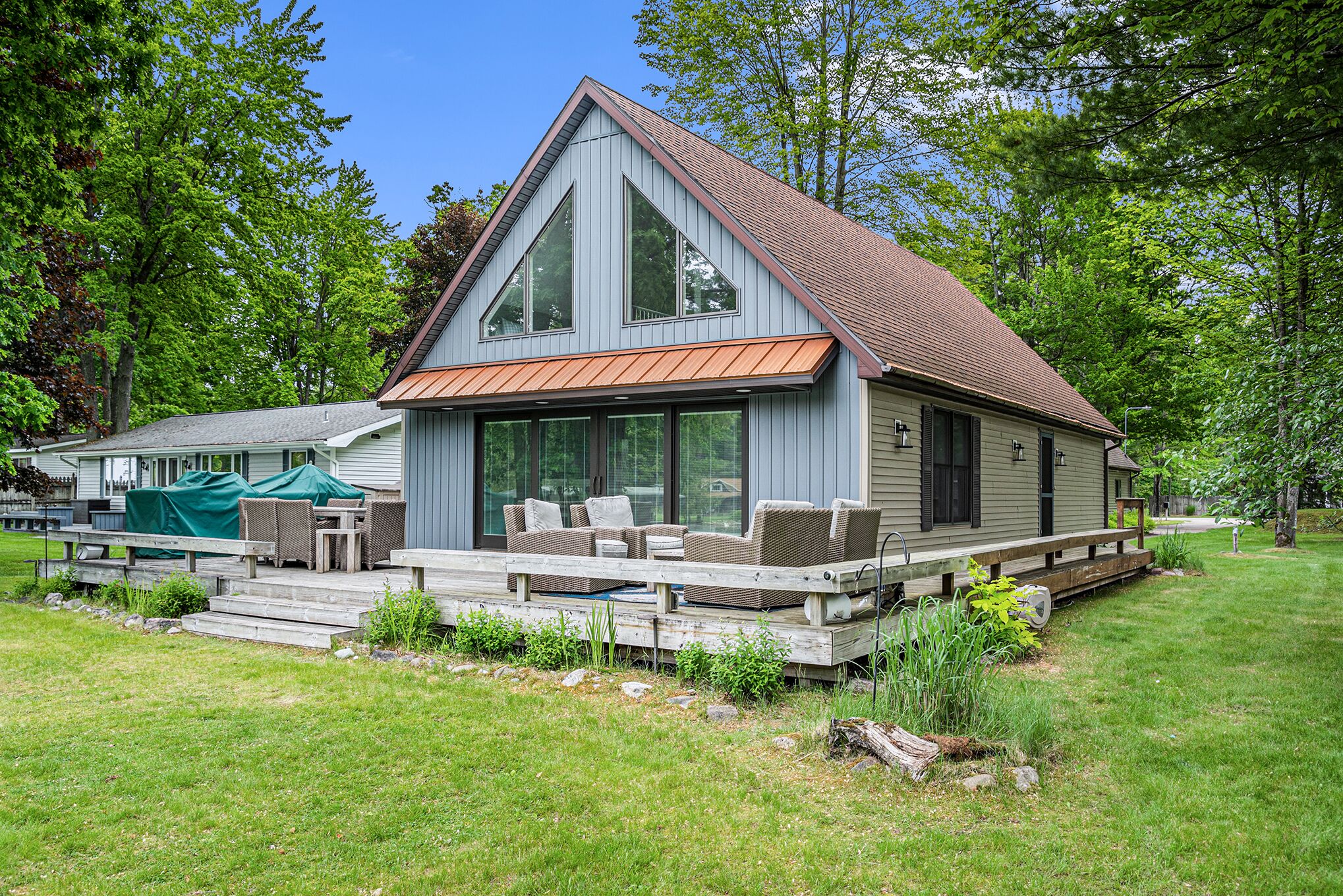 A two-story house with a covered patio, large windows, and a wooden deck.