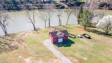 A red house with a white garage door, a gravel driveway, and a small trailer parked nearby.