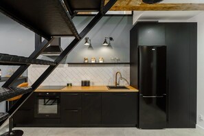 Uma cozinha moderna com armários pretos, bancada de madeira, geladeira preta e forno embutido.