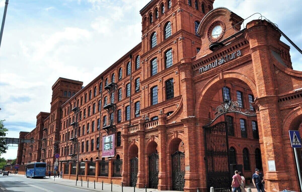 A large brick building with arched windows and a clock tower, likely a historical or industrial site.