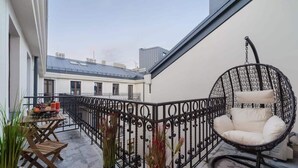 A balcony with a wicker chair, a table with fruits and drinks, and potted plants. - Lumina spacious 2-levels apart (Lódz)