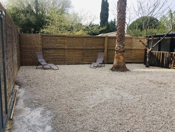 Un patio de grava con dos sillones y una valla de madera.