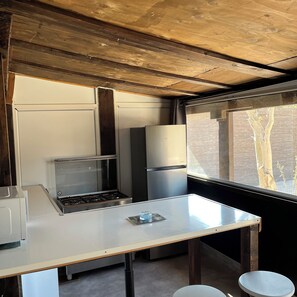 Una cocina compacta con estufa a gas, un refrigerador y una ventana que ofrece vistas al exterior.
