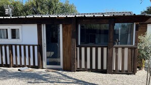 Eine Holzhütte mit Schiebetür, kleinem Fenster und einem Schotterweg.
