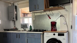 Eine kleine Küche mit Waschmaschine, Herd und Fernseher.