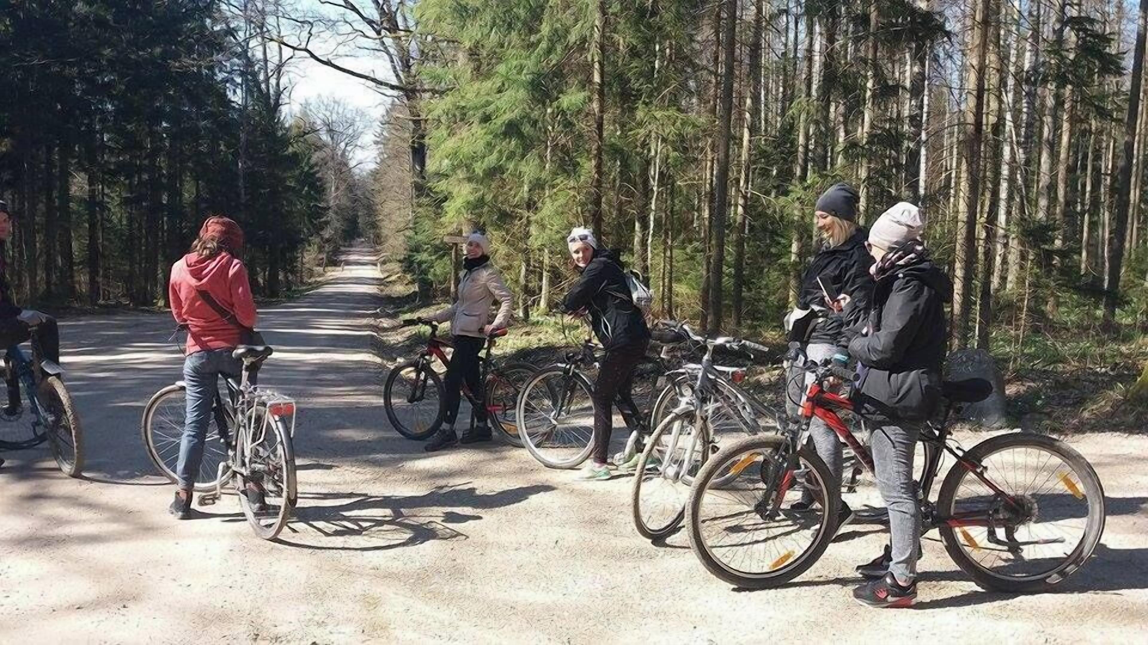Un grupo de ciclistas en un camino de tierra rodeado de árboles.