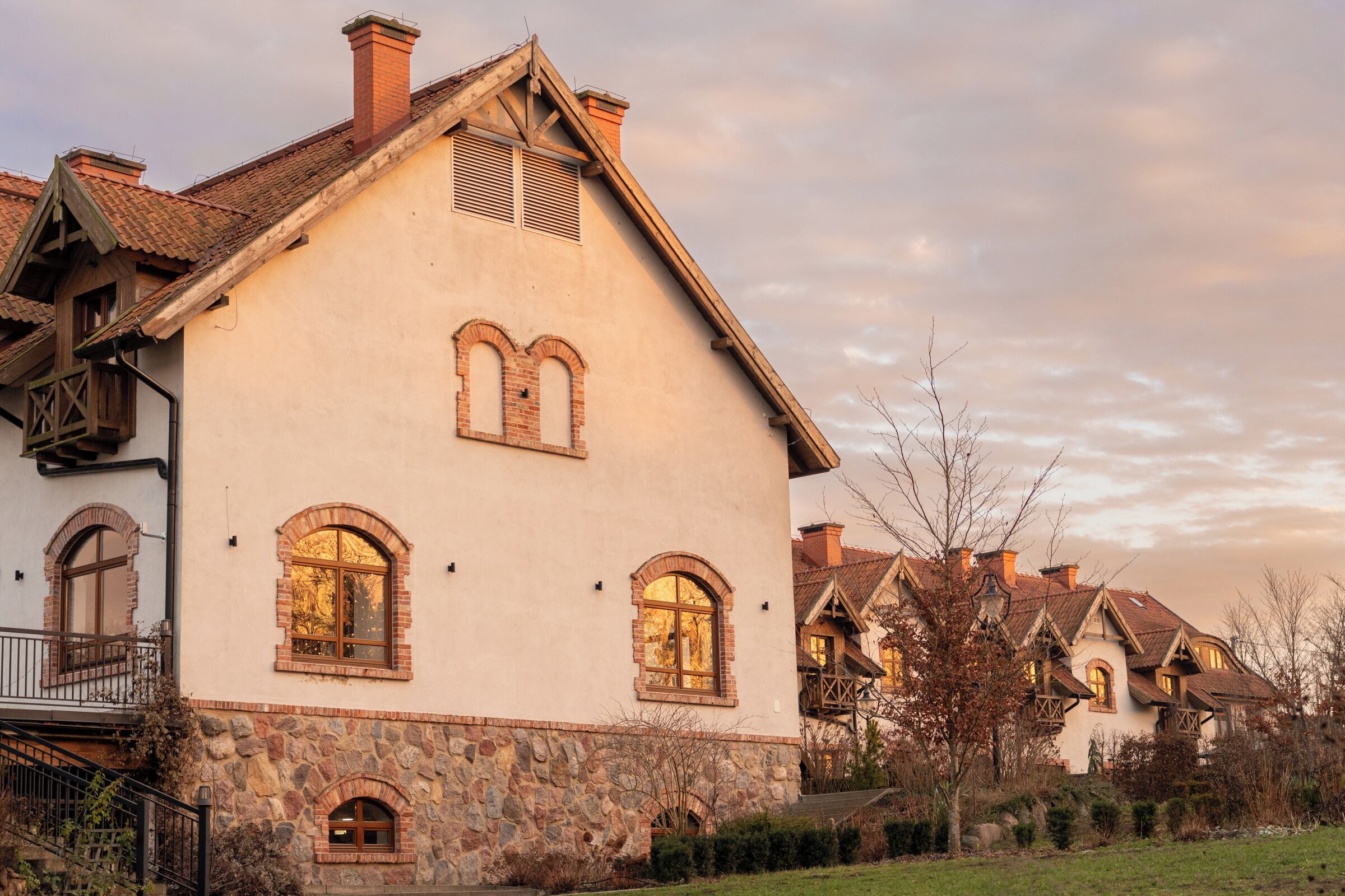 A large, two-story house with a stone foundation, multiple windows, and a sloped roof.