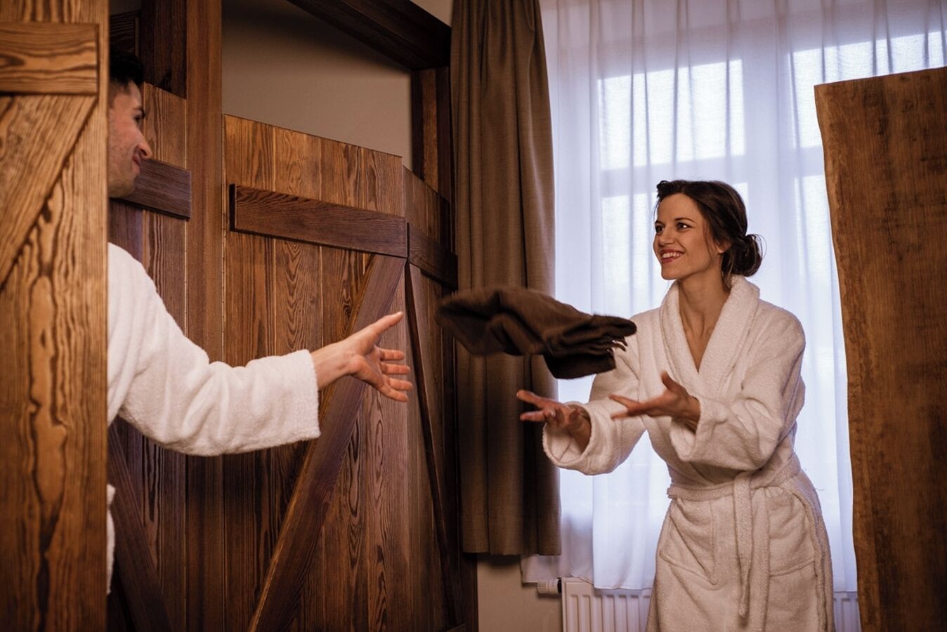 A wooden door with a person in a white robe reaching out to another person in a robe.