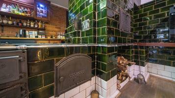 A bar area with a green-tiled backsplash, a wooden shelf with liquor bottles, and a television screen.