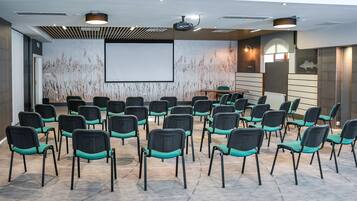 A conference room with rows of chairs, a projector screen, and a large wall mural.