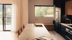 A modern kitchen with a large island, a built-in oven, and a window with a view of trees.