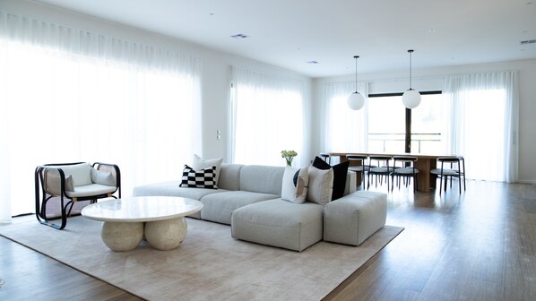 A modern living room with a sectional sofa, a round coffee table, and a dining area with chairs.