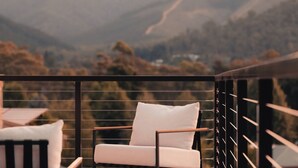 A balcony with a white chair and a cushion, overlooking a mountainous landscape.