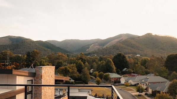 Zona residencial con casas, un edificio de piedra y una cadena montañosa al fondo.