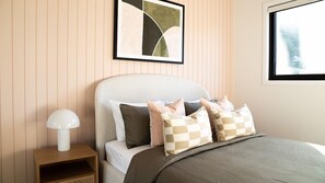 Une chambre à coucher avec un lit, des oreillers, une table de chevet et une lampe.