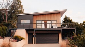 A modern two-story house with a balcony, a garage, and a staircase leading to the upper level.