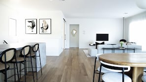 A modern living space with a dining area, a sofa set, and artwork on the walls.