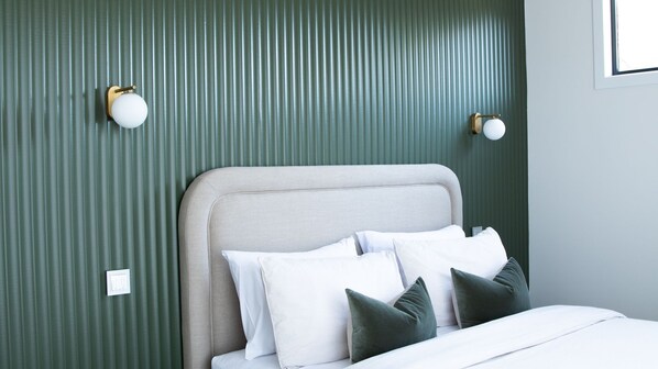 A bed with a headboard, pillows, and a wall with vertical lines.