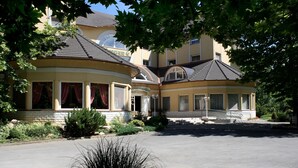 A two-story building with a curved facade, large windows, and a central entrance. - Hotel Arborétum (Harkany)