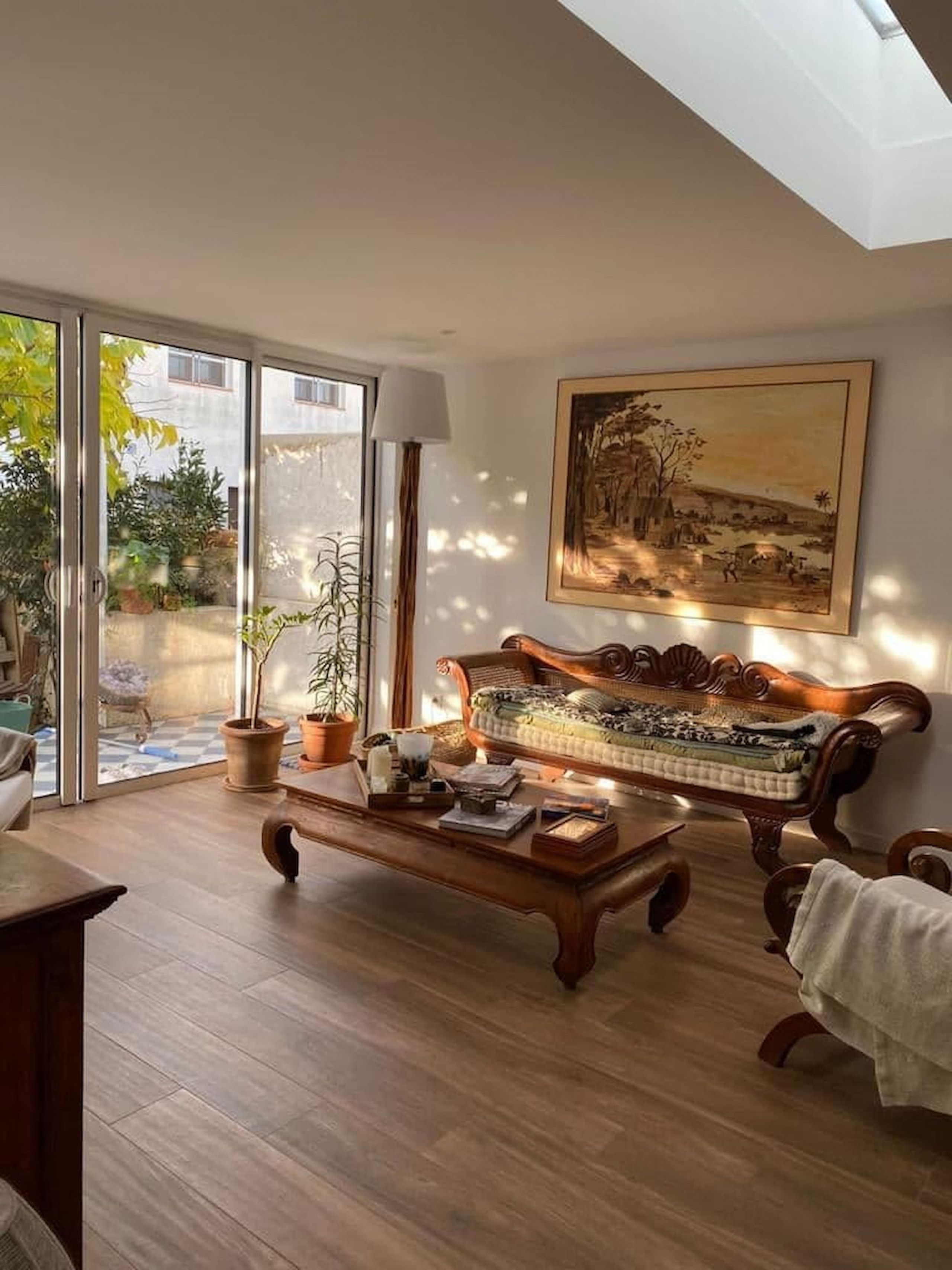Un salon spacieux avec une table basse en bois, un canapé et un grand tableau accroché au mur.