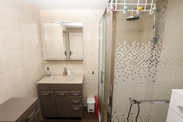 Et badeværelse med bruser, håndvask med spejl og toilet.