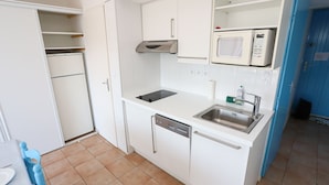 A compact kitchen with white cabinets, a built-in microwave, a dishwasher, and a sink.