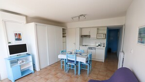 A compact living space with a dining area, kitchenette, and a television on a stand.