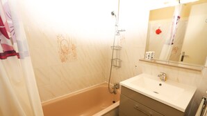A bathroom with a bathtub, a sink, and a mirror.